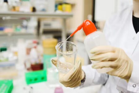 lab technician spraying liquid into a small beaker